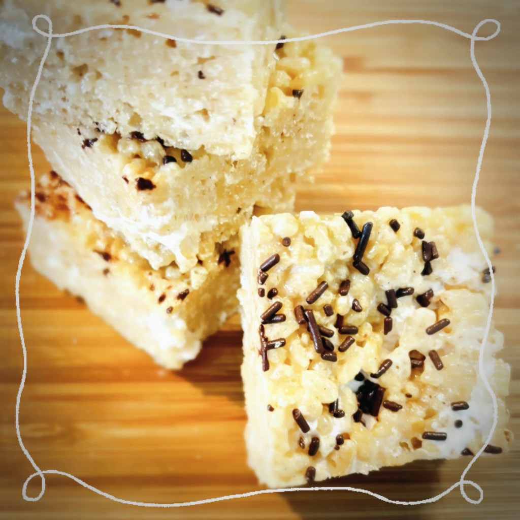 A small stack of coconut krispy rice treats, lightly dusted with chocolate sprinkles.