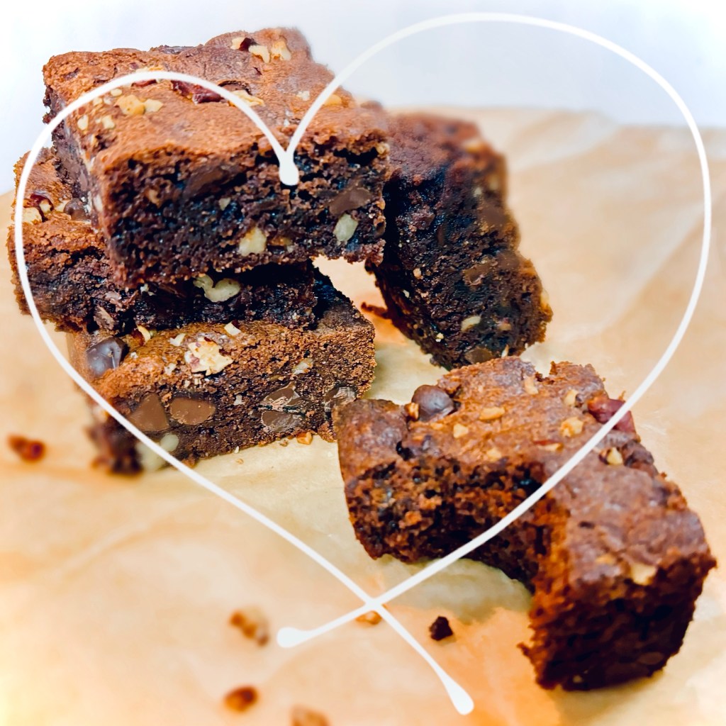 A small stack of pecan-studded brownies, with one which has a big bite taken from it.