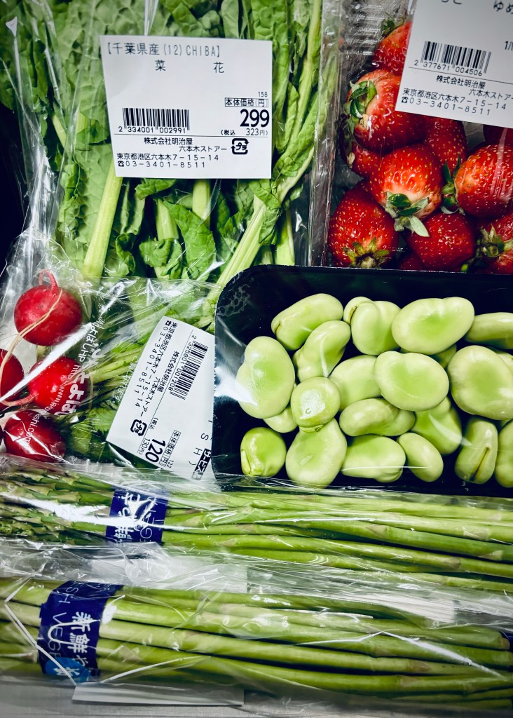 An image of some plastic wrapped vegetables, including broad beans, baby radishes, mustard greens, and two small bags of asparagus.