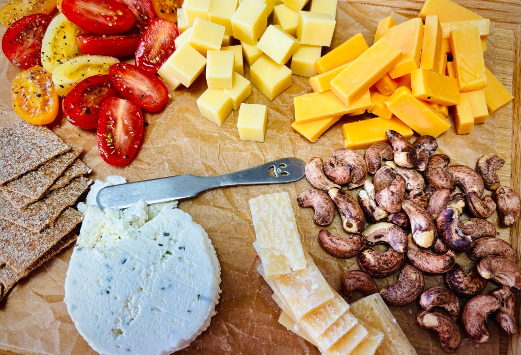 A wooden tray, lined with butcher's paper, had small mounds of different cheeses, crackers, nuts, and fruits to enjoy in lieu of lunch.